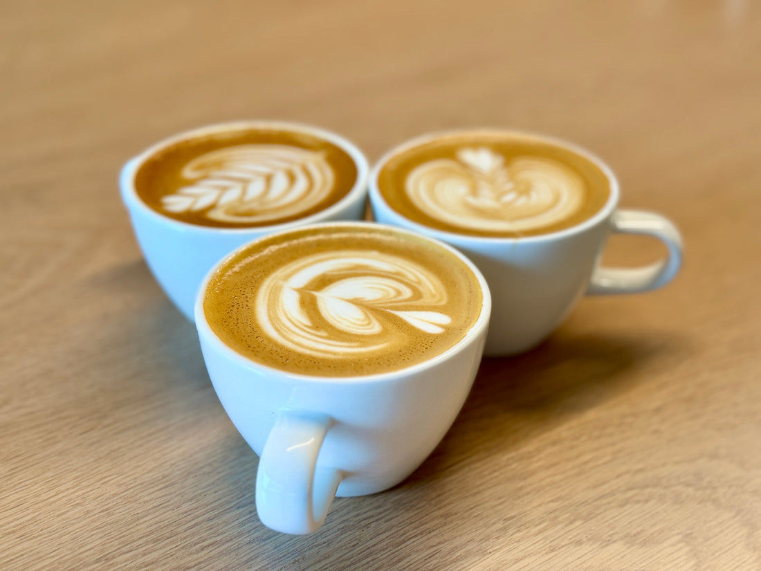 Three flat whites on a timber bench at Born & Raised
